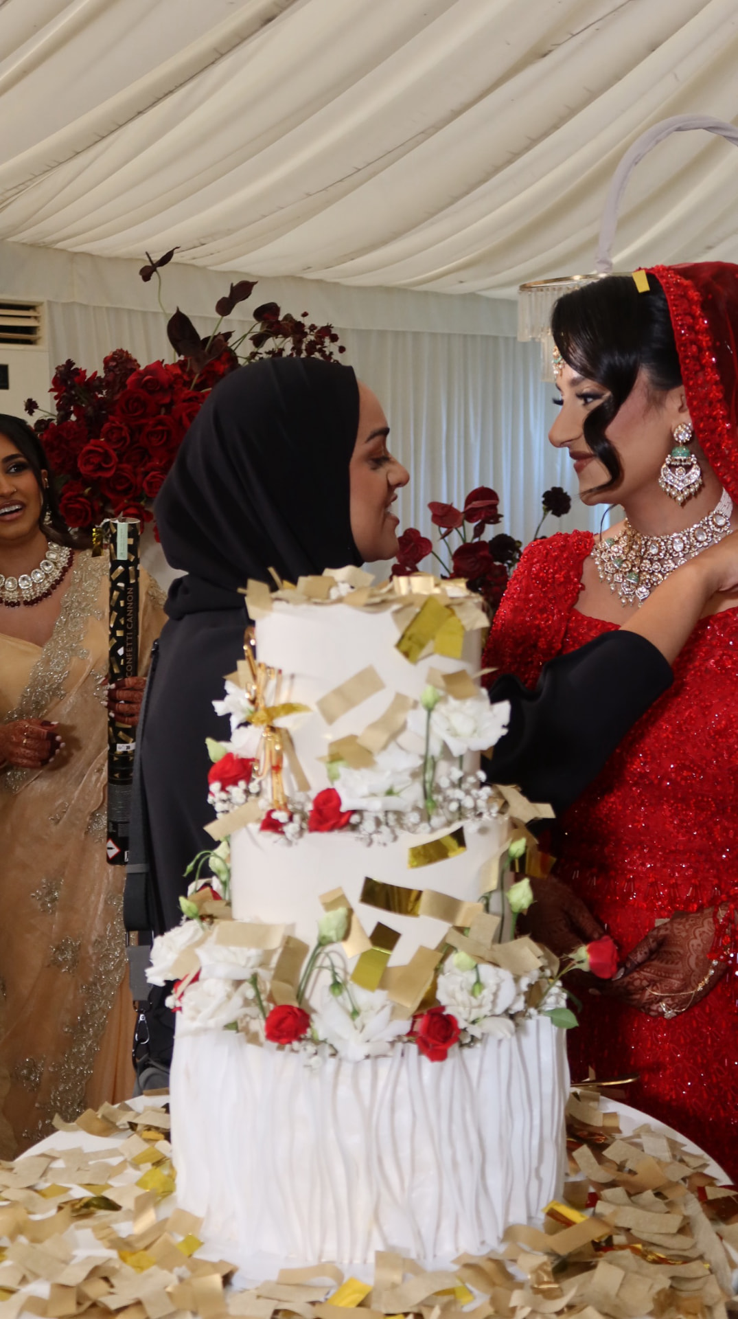 Coordinator with the bride at the cake table as gold confetti falls